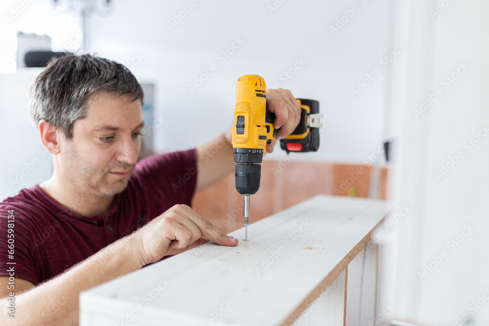 Man with electrical screwdriver. Kitchen assembly concept.