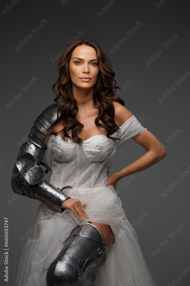 Fashion meets history: Brunette in luxurious dress and armor pieces on a neutral background Fashion meets history: Brunette in luxurious dress and armor pieces on a neutral background