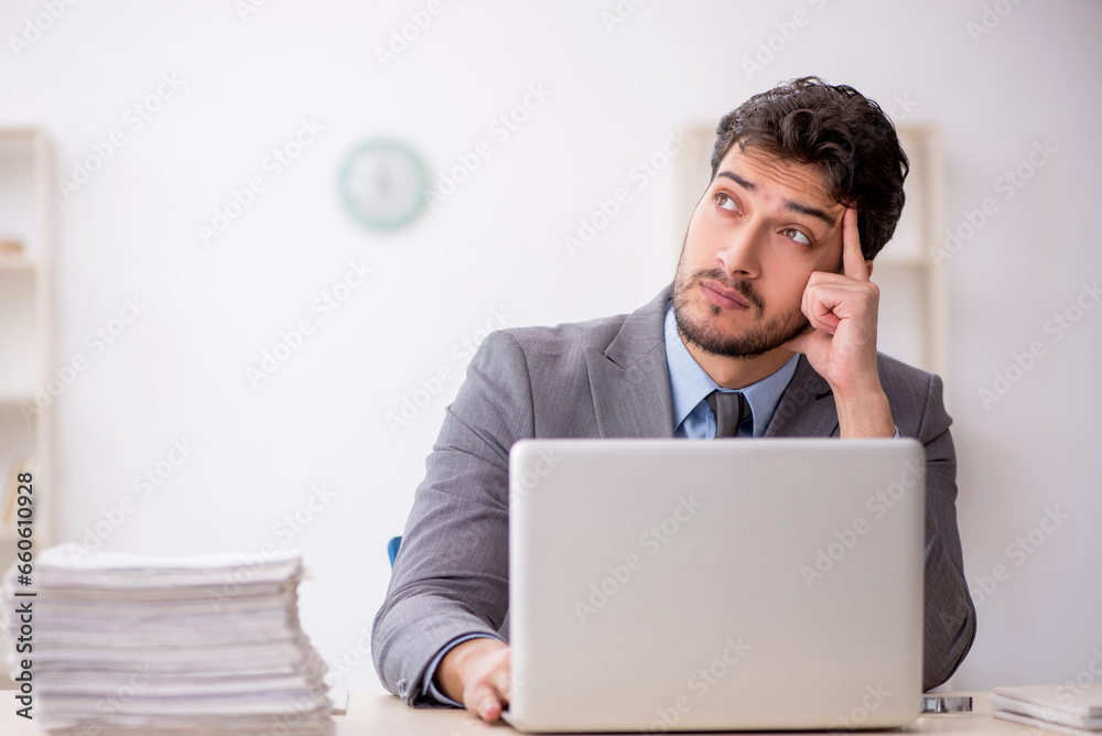 Young male employee and too much work in the office Young male employee and too much work in the office