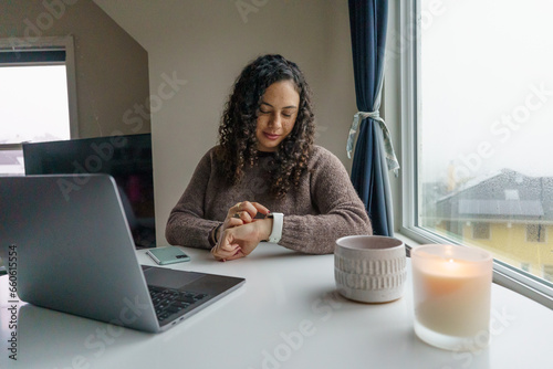 Curly hair young woman working on laptop in cozy nook with mug	