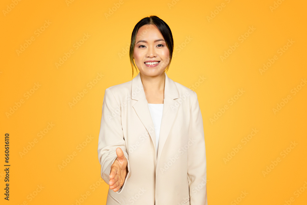 Millennial Asian woman in yellow, extending hand warmly for a handshake, welcoming gesture Millennial Asian woman in yellow, extending hand warmly for a handshake, welcoming gesture
