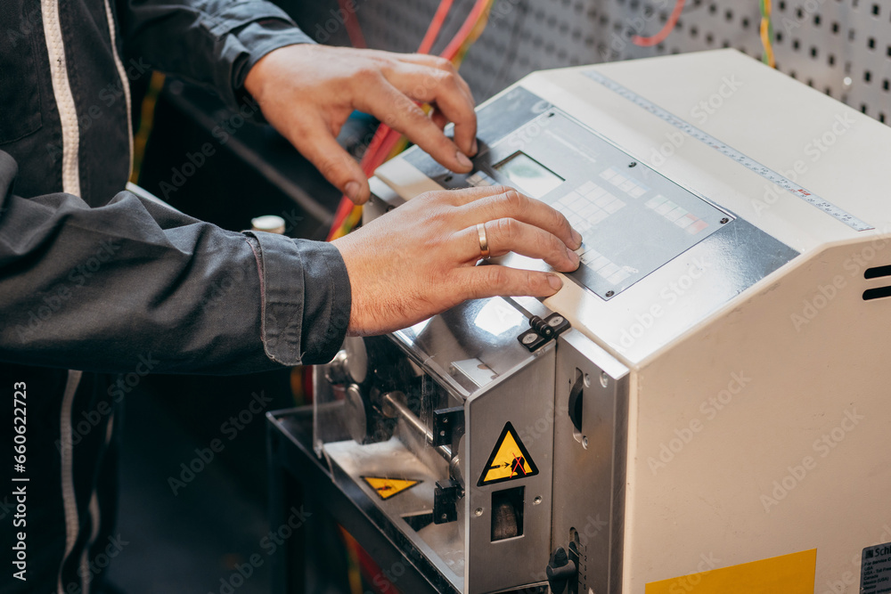 Hands of electrician working on cutting wires machine