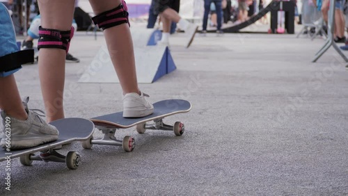 Male skater legs doing tricks on skateboarding city park, skateboarder feet while skating in city, view from the back photo