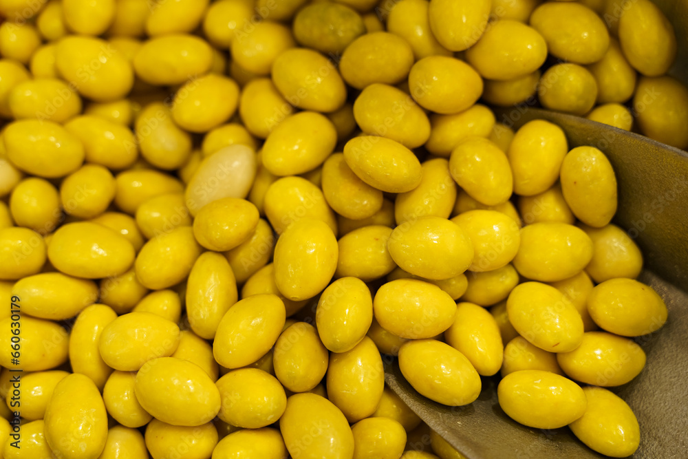 There are candies on the counter - peanuts in yellow glaze and a spoon.