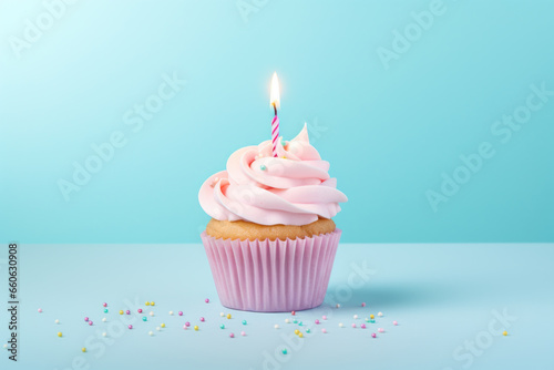 Birthday cupcake with candles on pastel colored background