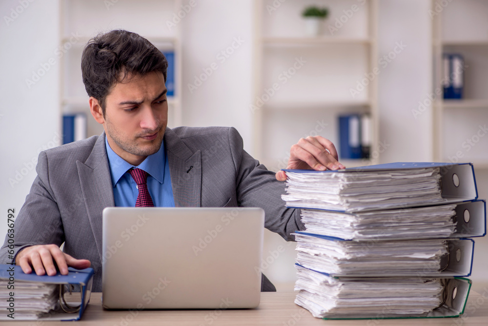 Young male employee and too much work in the office Young male employee and too much work in the office