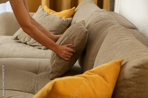 Woman arranging sofa cushion in living room	