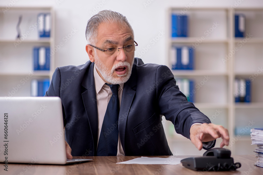 Old male employee working in the office Old male employee working in the office