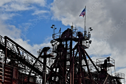 American flag flies proudly on top of old seed distribution manifold tower with metal walkways and platforms from bygone era 