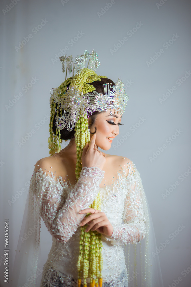 Close-up image of a Javanese bride with a large, elaborate *konde* bun adorned with flowers and jewelry.