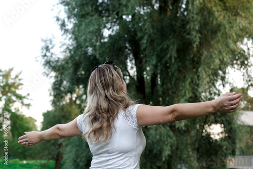 Woman rejoices in the park raising her arms up and spinning