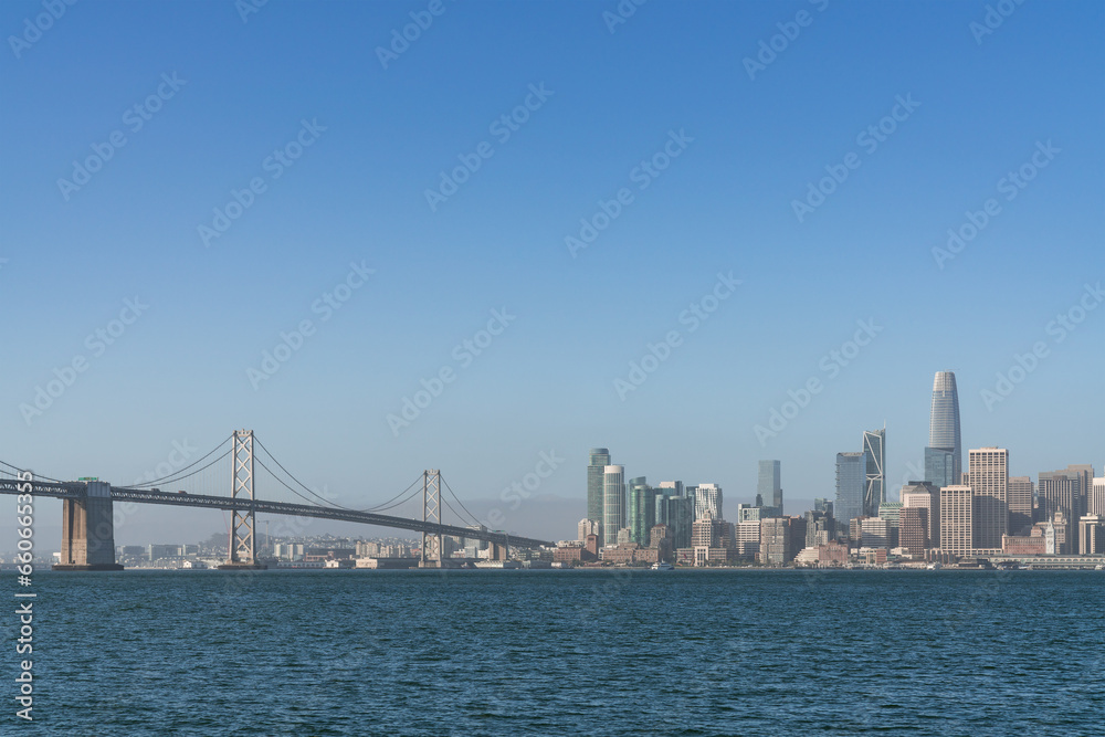 A picturesque skyline of San Francisco Panorama at sunrise from Treasure Island, California, United States. Panoramic view of cityscape with mist and foggy air at morning day time.