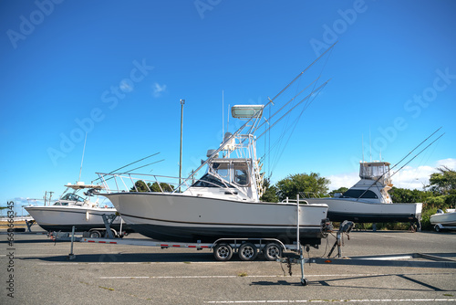 Large motor boats on car trailers parked at the pier.