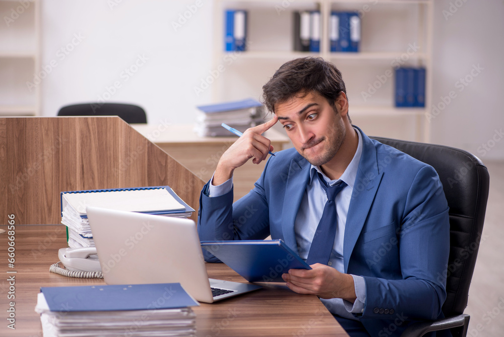 Young male employee and too much work in the office Young male employee and too much work in the office