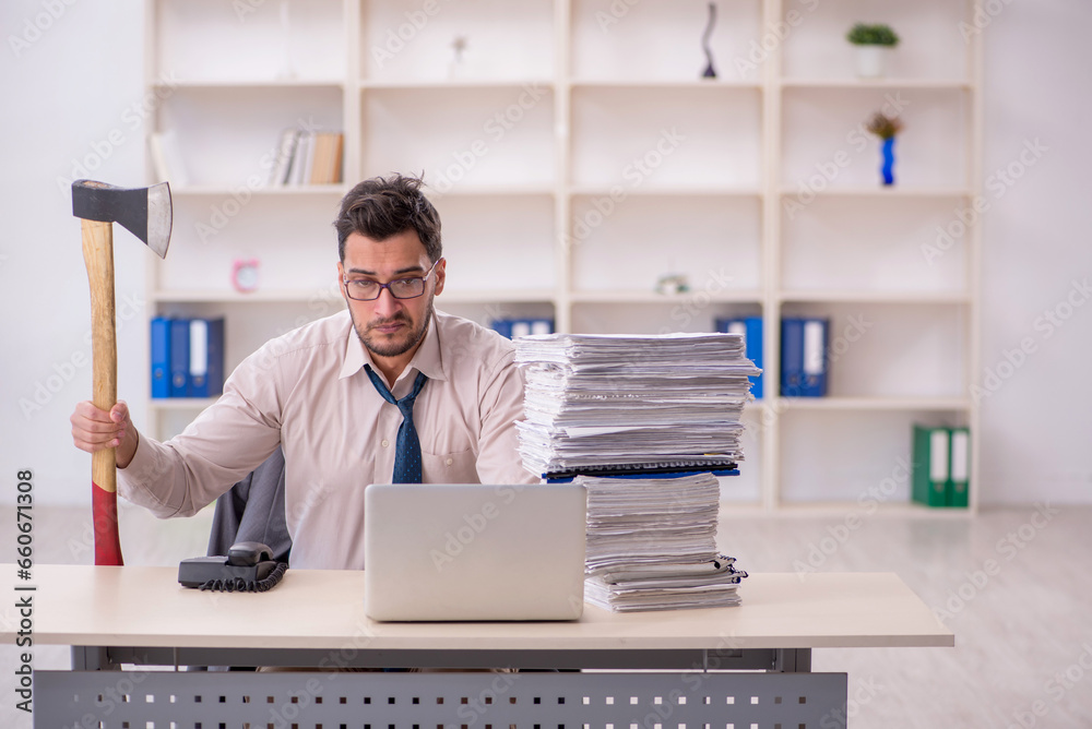 Young male employee unhappy with excessive work in the office Young male employee unhappy with excessive work in the office