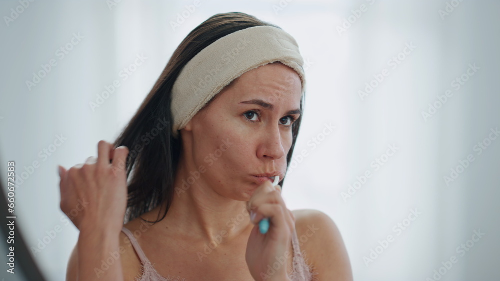 Serious woman brushing teeth at bath room closeup. Lady caring of dental hygiene Serious woman brushing teeth at bath room closeup. Lady caring of dental hygiene