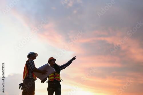 Two construction workers on a building site at sunset, Thailand photo