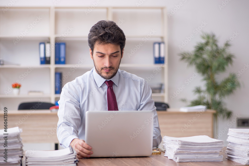 Young male employee and too much work in the office Young male employee and too much work in the office