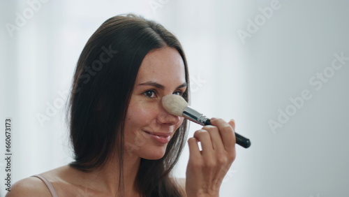 Happy woman applying powder apartment closeup. Smiling lady putting cosmetics