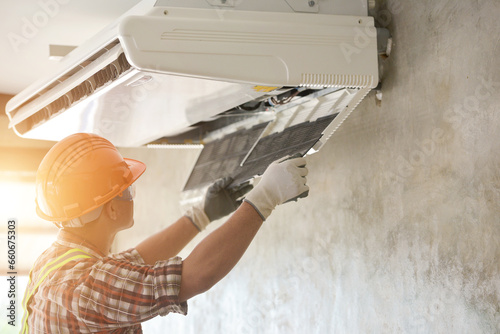 Electrician installing an air conditioning unit on a wall, Thailand