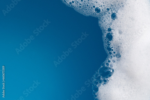 Detergent foam bubble on water. Blue background, Soap sud photo