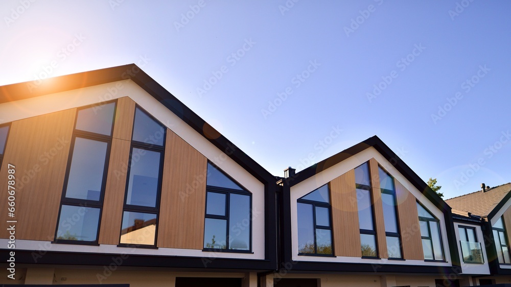 Suburban neighborhood with condominium complex. Suburban area with modern geometric family houses. Row of family houses against blue sky.