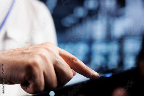 Cloud computing business executive using laptop to examine servers for power fluctuations  close up. Adept worker monitoring high tech data center components  identifying potential glitches