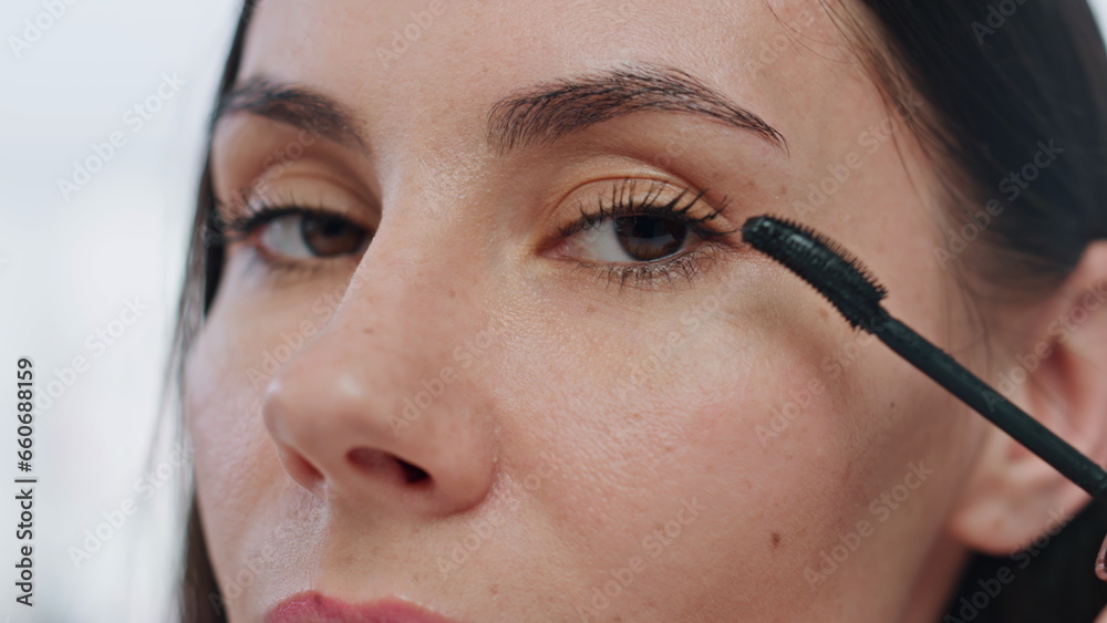 Closeup lady applying eyelashes mascara makeup indoors. Pov serious woman visage