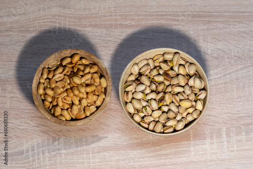 peanuts and pistachios on a wooden background in wooden bowls
