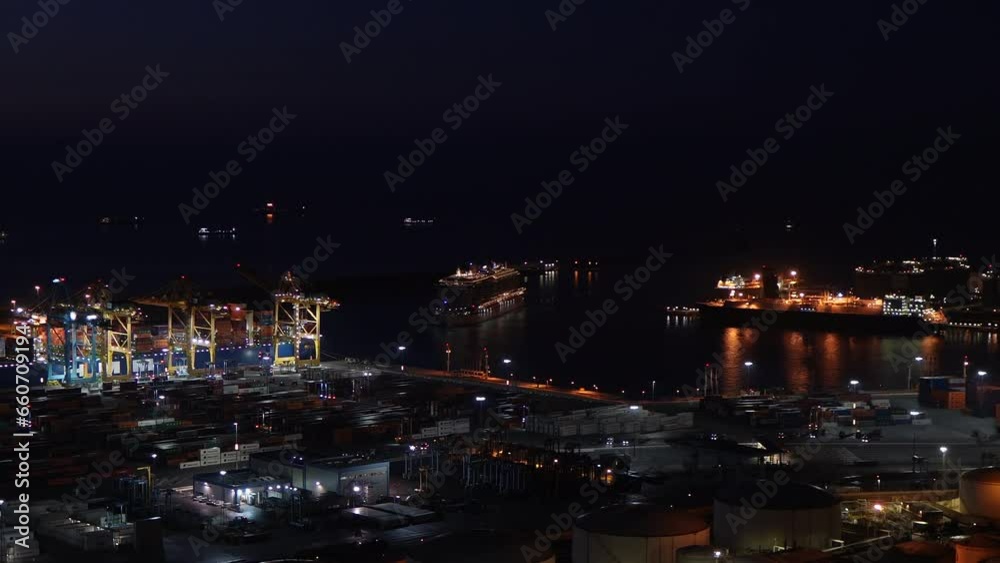 Nightfall brings life to an industrial port, with cranes and tanks lit under the 4K drone's gaze. Horizontal view with copyspace. Nightfall brings life to an industrial port, with cranes and tanks lit under the 4K drone's gaze. Horizontal view with copyspace.