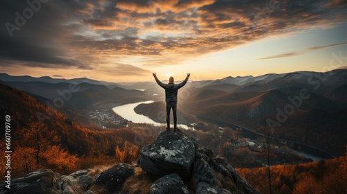 Man raises one hand punching the air on mountain peak with sunset background no face back view © MBRAMO