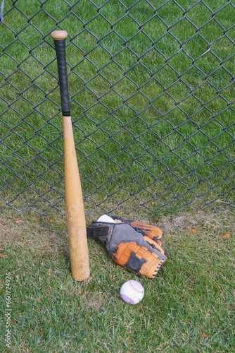 Baseball Bat, Glove and Ball near Cyclone Fence photo