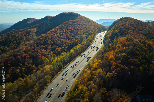 View from above of I-40 freeway in North Carolina heading to Asheville through Appalachian mountains in golden fall season with fast driving trucks and cars. Interstate transportation concept