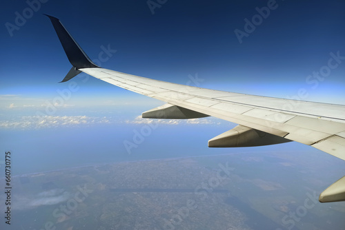 View through airplane window of commercial jet plane wing flying high in the sky. Air travelling concept