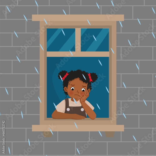 Cute little African girl looking at raindrops from window feeling sad can not play outside