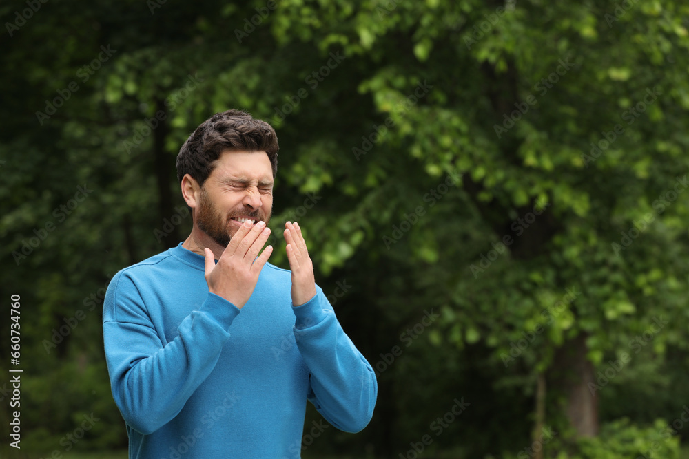 Man suffering from seasonal spring allergy outdoors, space for text Man suffering from seasonal spring allergy outdoors, space for text