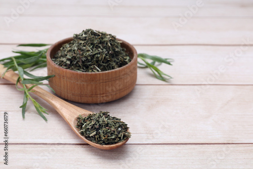 Dry and fresh tarragon on wooden table, space for text