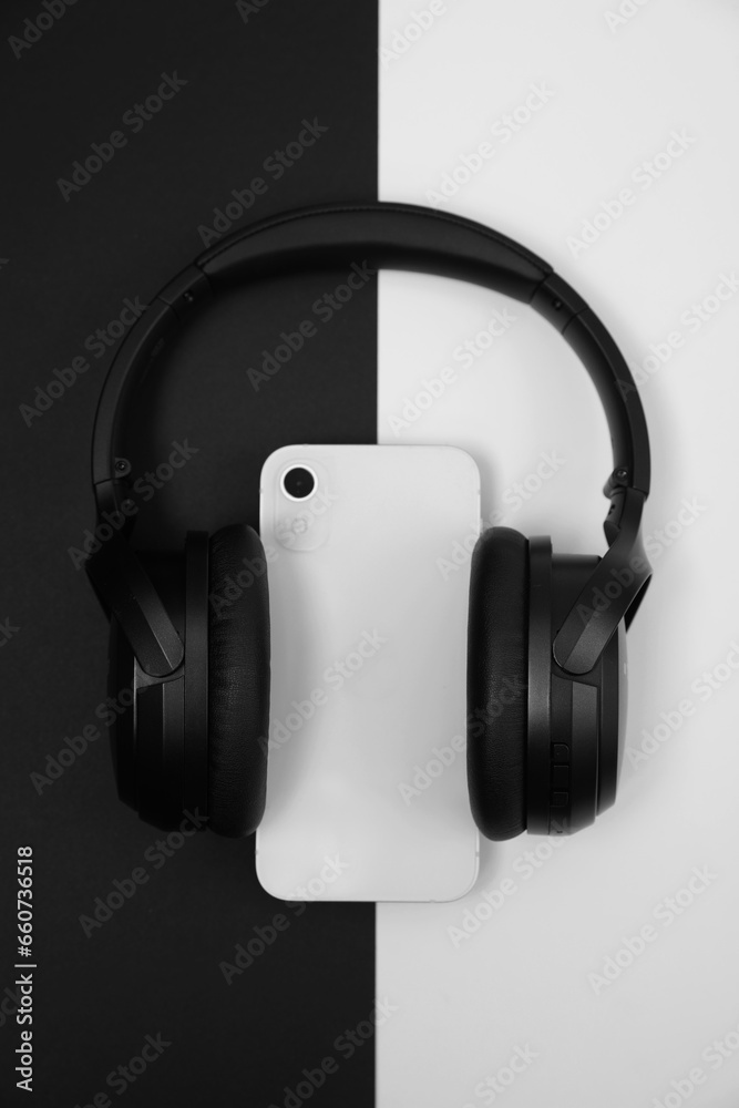 Modern wireless headphones and smartphone on color background, top view