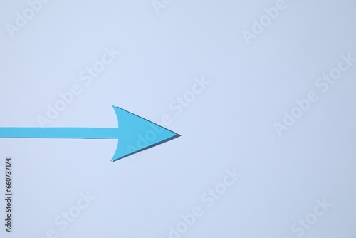 Light blue paper arrow on white background  top view. Space for text