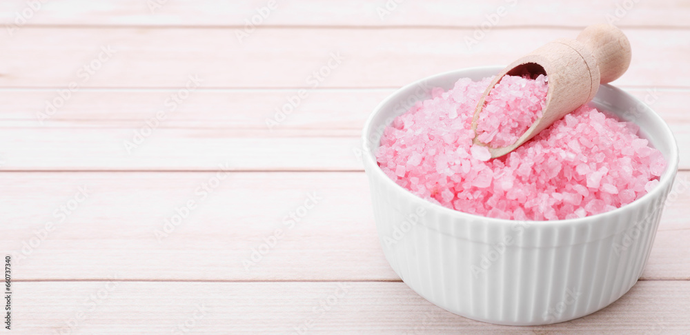 Bowl and scoop with sea salt on light wooden table, closeup. Banner design with space for text Bowl and scoop with sea salt on light wooden table, closeup. Banner design with space for text