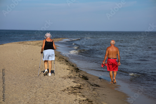 Elderly couple walking on the beach in the summer day.