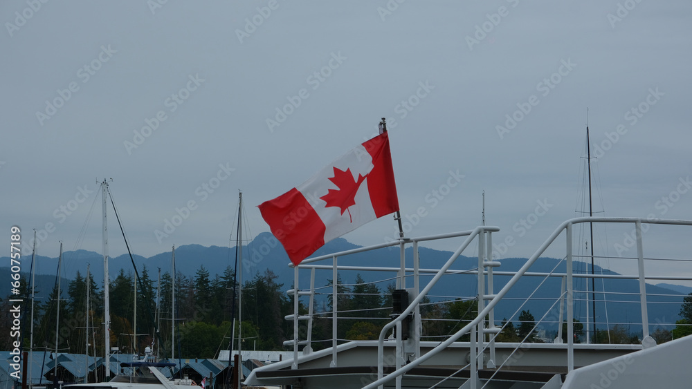 Fototapeta premium Flag of Canada on a yacht waving in the wind on a dark cloudy day
