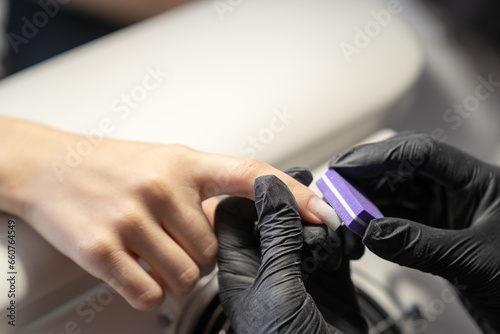 Female hands and tools for manicure  process of performing manicure in beauty salon. Nail care procedure in a beauty salon. Gloved hands of a skilled manicurist cutting cuticles. Concept spa body care