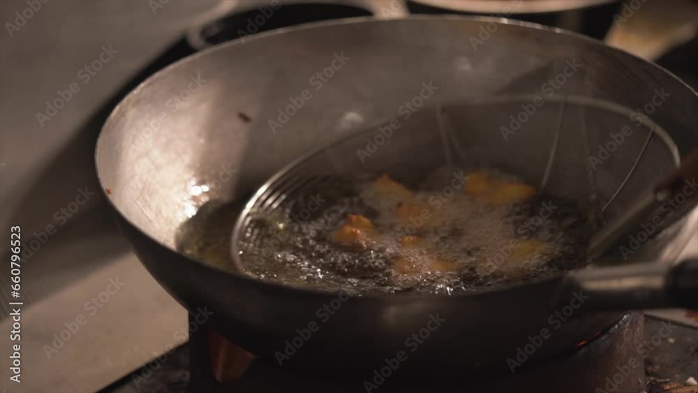 chef cooking deep-fried prawns in the big pan closeup view