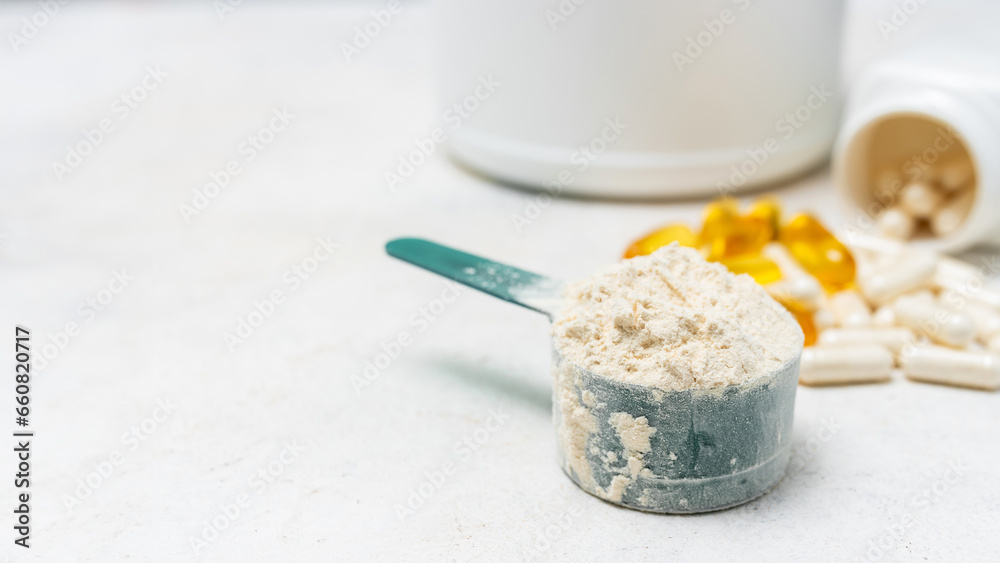 Whey protein powder in measuring spoon, white capsules of amino acids, vitamins and yellow capsules omega 3 on white background, healthy eating and bodybuilding food supplements Whey protein powder in measuring spoon, white capsules of amino acids, vitamins and yellow capsules omega 3 on white background, healthy eating and bodybuilding food supplements