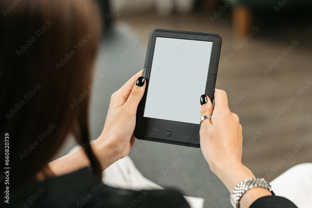Young woman sitting the couch with an e-book