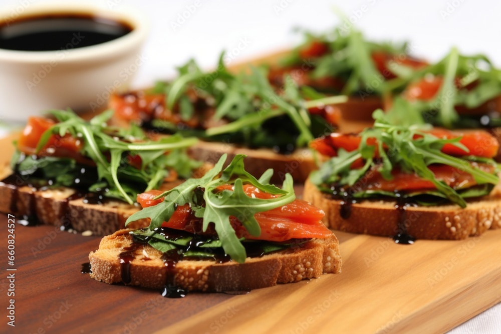 slices of toasted bread with chopped tomatoes, arugula, and balsamic glaze