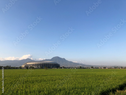The beauty of the Gelora Bandung Lautan Api Stadium with a view of rice fields and mountains in Bandung photo