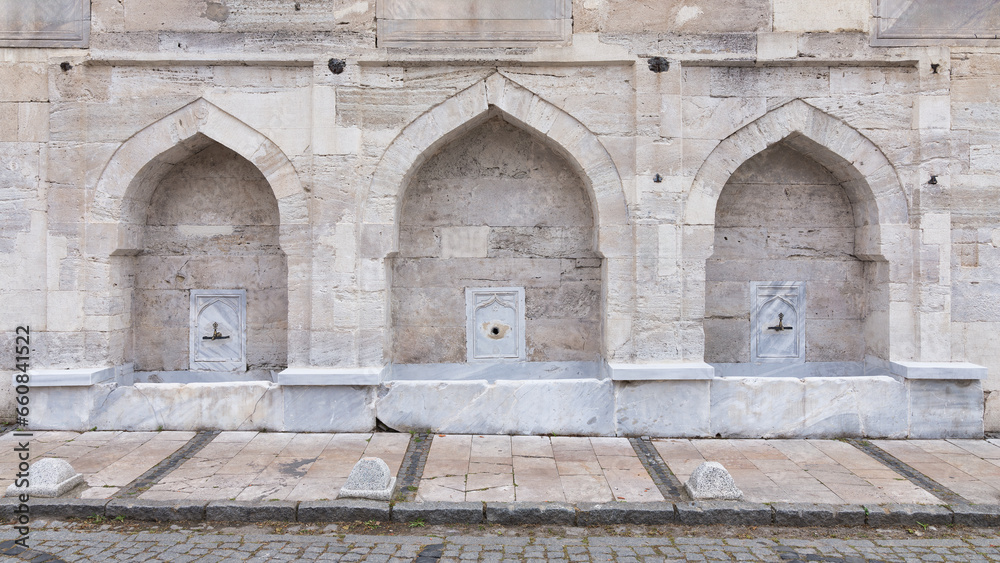 External stone wall of 16th century historic Atik Valide Mosque with row of ablution fountains, located in Uskudar, Istanbul, Turkey, built by Nurbanu Sultan, the mother of Sultan Selim II