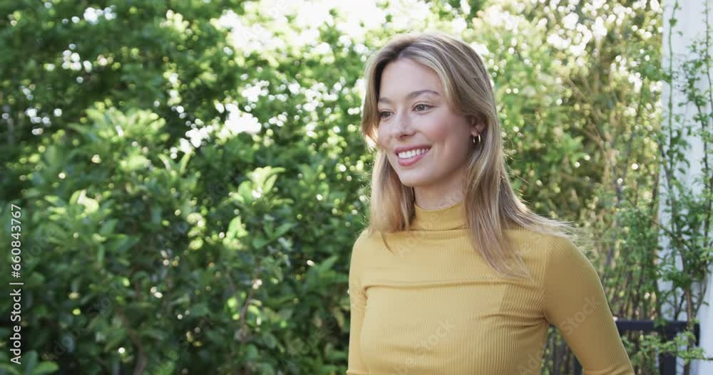 Portrait of happy biracial woman with blonde hair in garden, slow motion, copy space Portrait of happy biracial woman with blonde hair in garden, slow motion, copy space